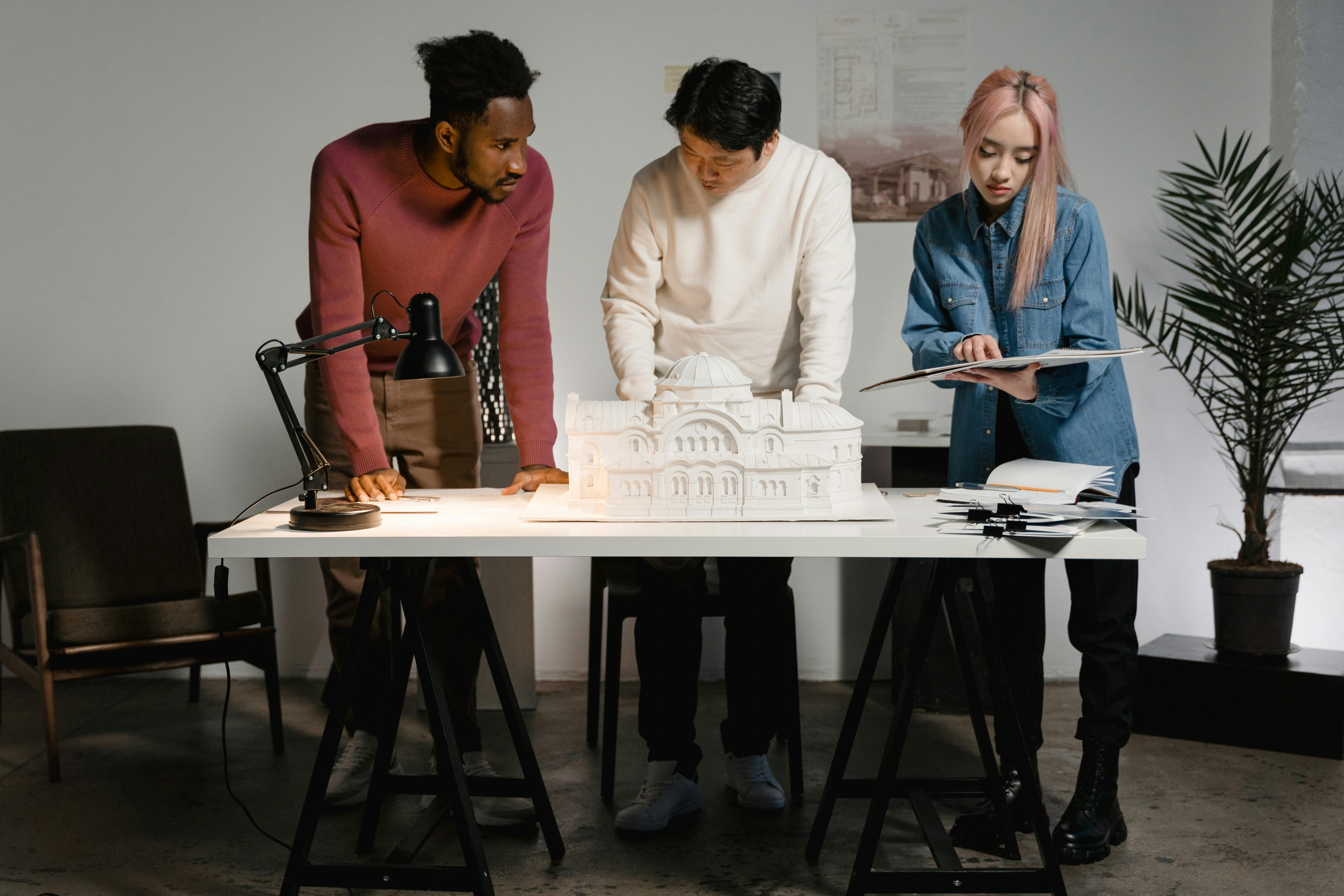 Three architects collaborating around a scale model on a table, discussing plans.